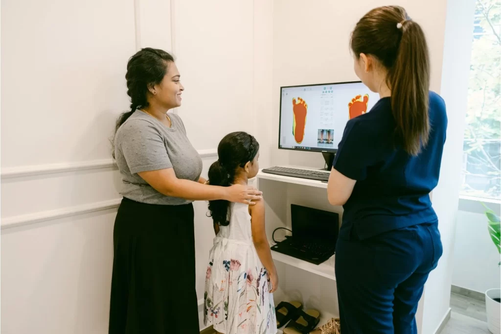 Podiatrist assessing child's flat feet through a 3D foot scanner.